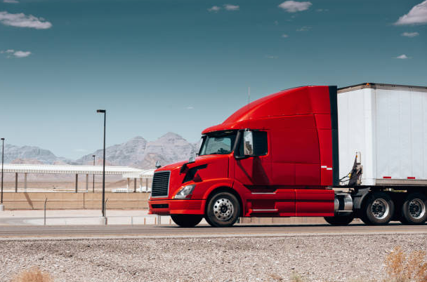 "Photograph of a red semi-truck on a highway under a clear sky, overlaid with digital icons representing safety, compliance, and temperature control for logistics."